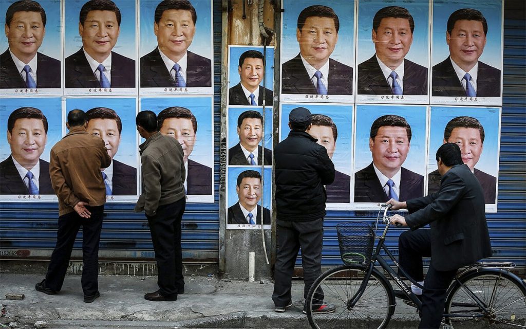 En esta foto del 26 de marzo de 2016, la gente mira un edificio cubierto con carteles del presidente chino Xi Jinping en Shanghai