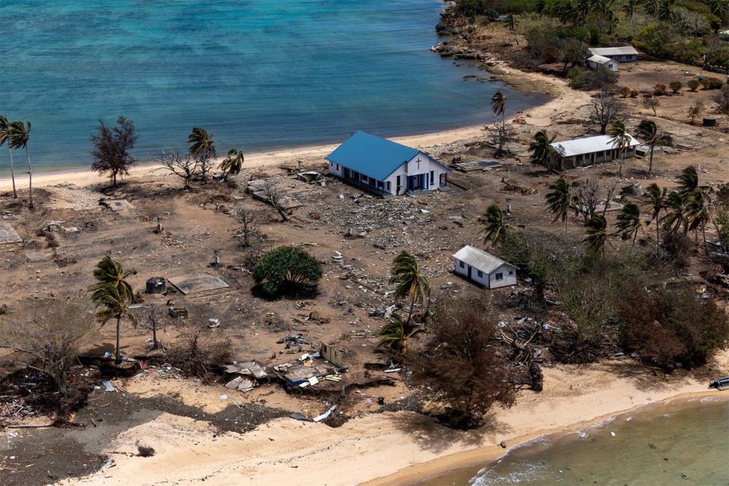 Escombros de varios edificios dañados y una iglesia. Los árboles están esparcidos en la isla de Atata en Tonga, el 28 de enero de 2022